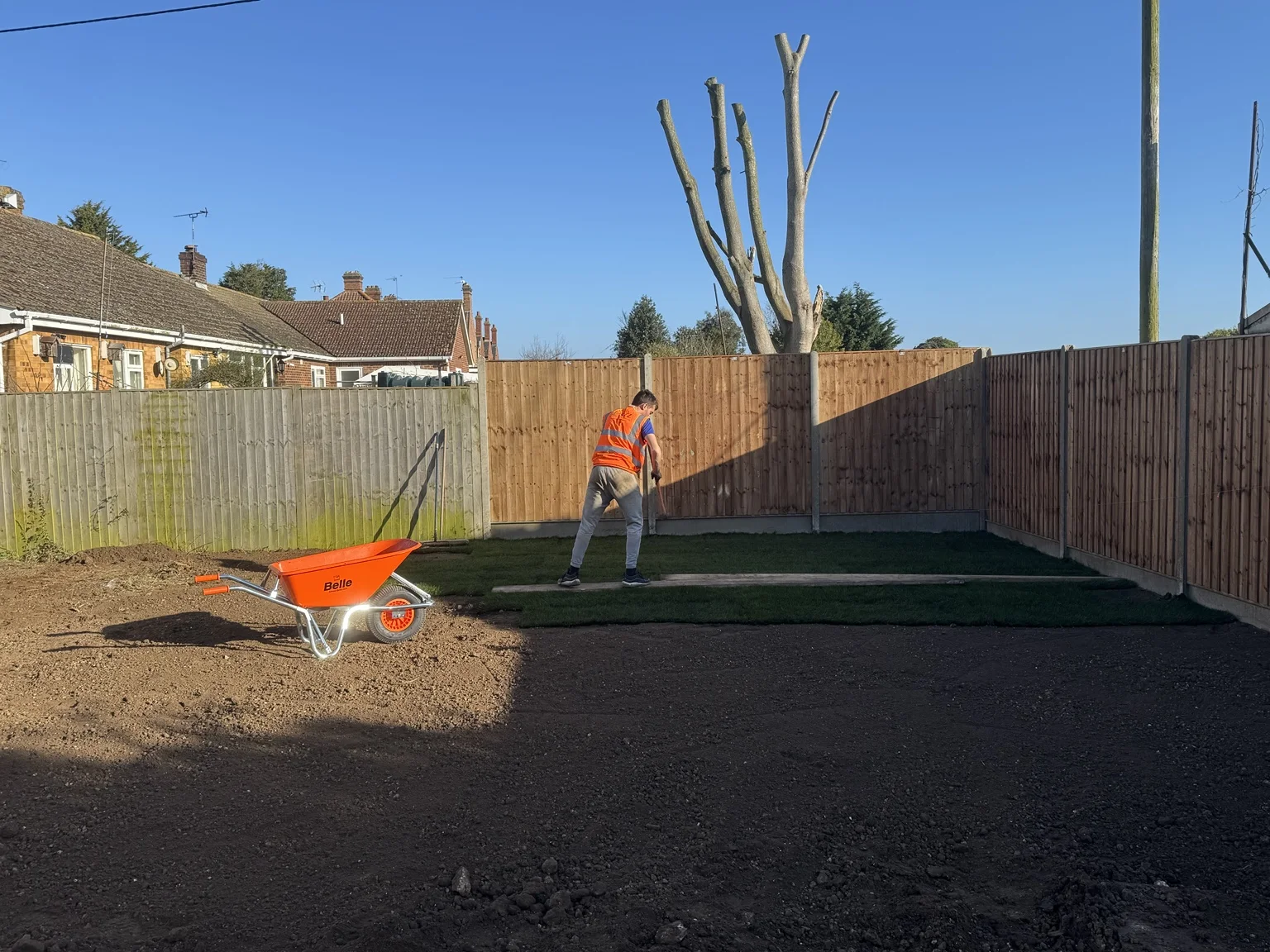 Turf laying in progress alongside timber garden fencing